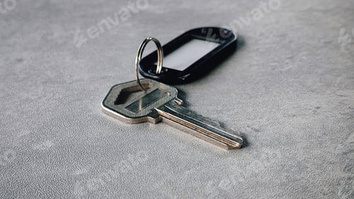 Preview: Metallic Key with Black Plastic Key Tag on Gray Surface