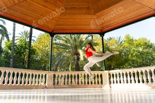Preview: Fitkid dancer performing split jump in park gazebo