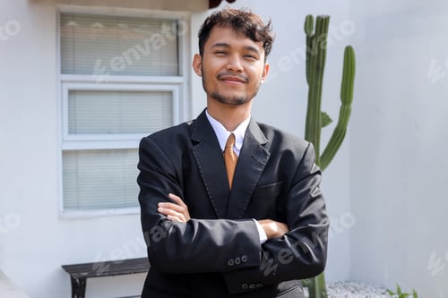 Preview: Confident professional Businessman in Dark Suit Stands Smiling Outdoors With His Arms Crossed