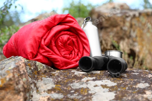 Preview: Rolled sleeping bag and other camping gear outdoors