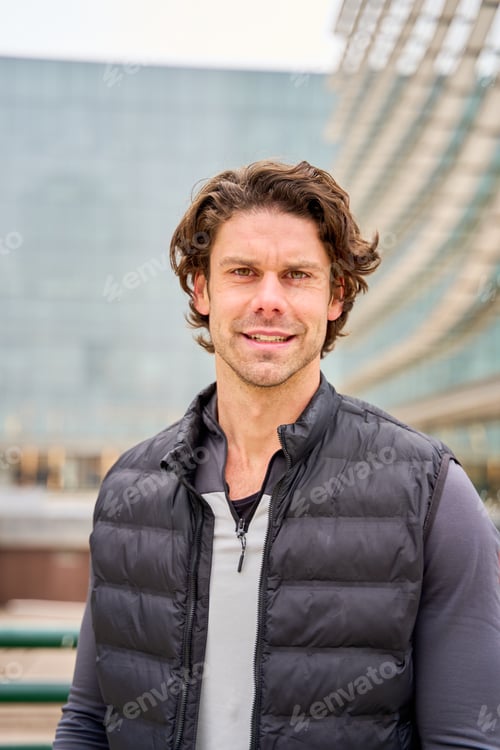 Preview: Portrait of smiling sportsman wearing vest in urban setting