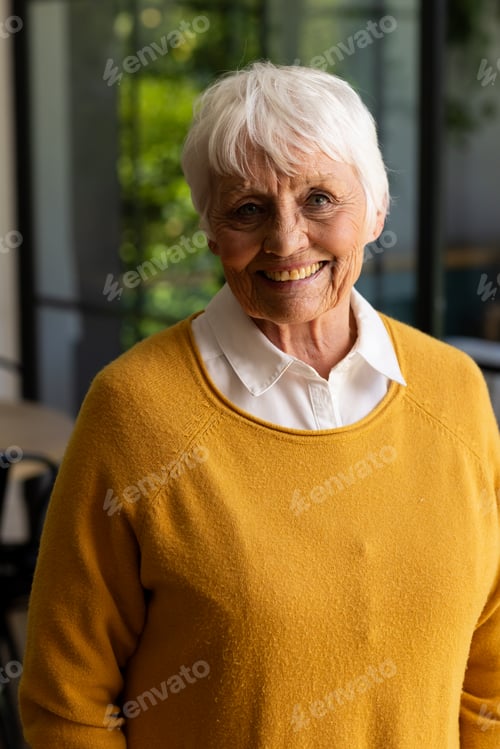 Preview: Portrait of happy caucasian senior woman with short white hair smiling in sunny kitchen at home