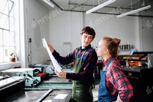 Preview: Young male and female craftsperson looking at print in book arts workshop