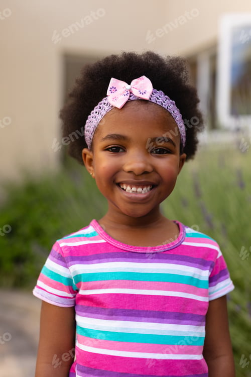 Preview: Portrait of smiling cute african american girl wearing striped t-shirt and headband