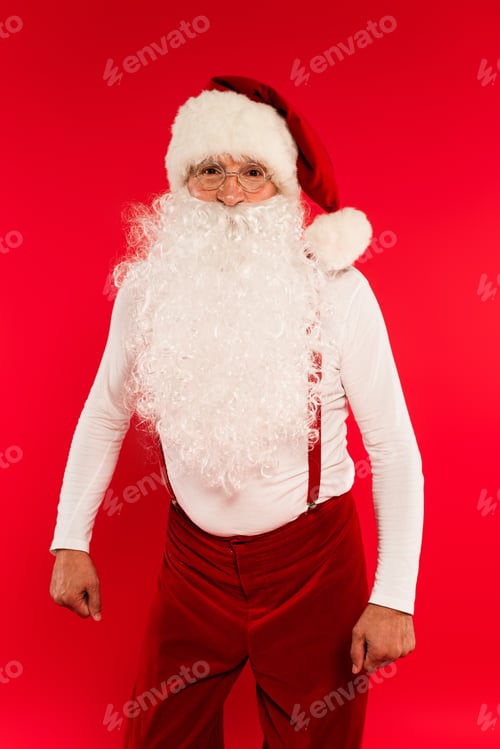 Preview: Santa claus in eyeglasses looking at camera isolated on red