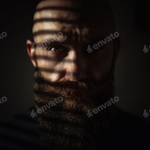 Preview: Close-up portrait of middle aged brutal bearded man with expressive eyes and striped shadows on face