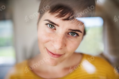 Preview: Front view of young woman standing indoors at home, close-up.