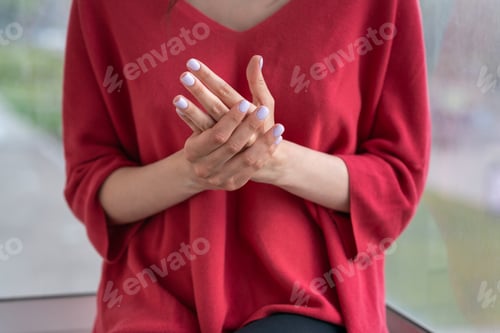 Preview: girl sits on the windowsill and applies cream on her hands
