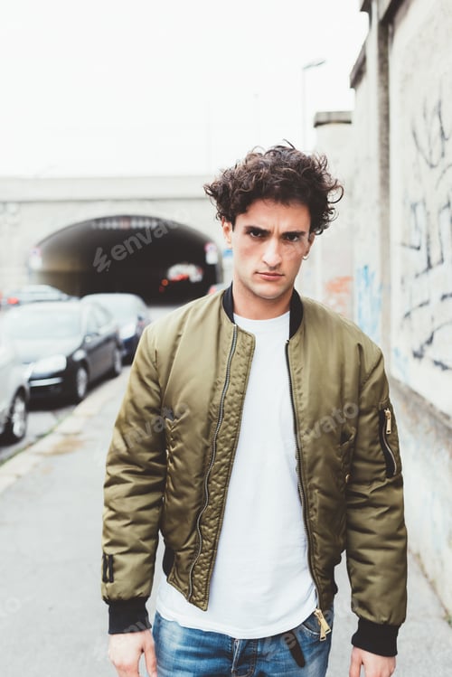 Preview: Man in Olive Jacket Stands by City Street