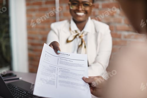 Preview: Close-up of black businesswoman giving her resume during job interview in the office.