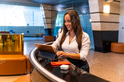 Preview: Spanish Businesswoman. Hotel counter. Hotel worker reviewing the day's reservations.