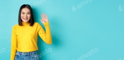 Preview: Portrait of beautiful asian girl with happy smile, waving hand to say hello, greeting you with