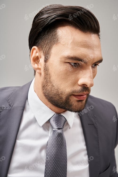Preview: close up photo of worried businessman in formal wear looking away while thinking on grey