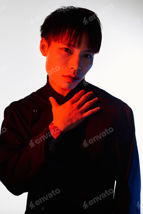 Preview: Stylish young asian man posing confidently in vibrant lighting at a creative studio