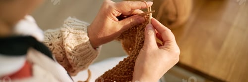 Preview: Close-Up of Hands Knitting Cozy Sweater with Beige Yarn