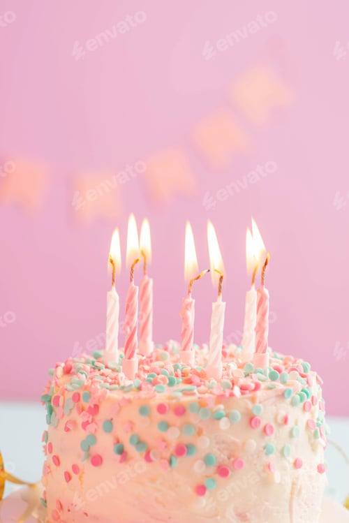 Preview: Festive cake with candles on the background of a festive pink wall with flags. Holiday concept