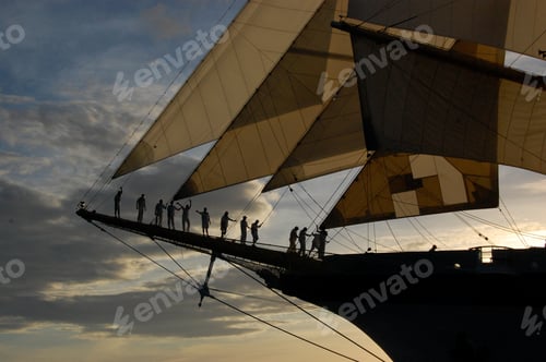 Preview: Crew of sailing ship standing together on the bow at sunset.