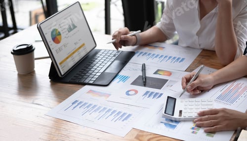 Preview: Two women analyzing documents while sitting on a table in office. Woman executives at work in office