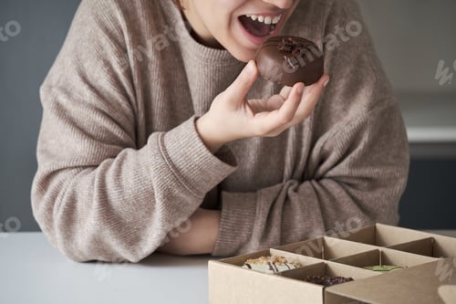 Preview: Unrecognizable woman eating chocolate donut from crafted donuts takeaway box.