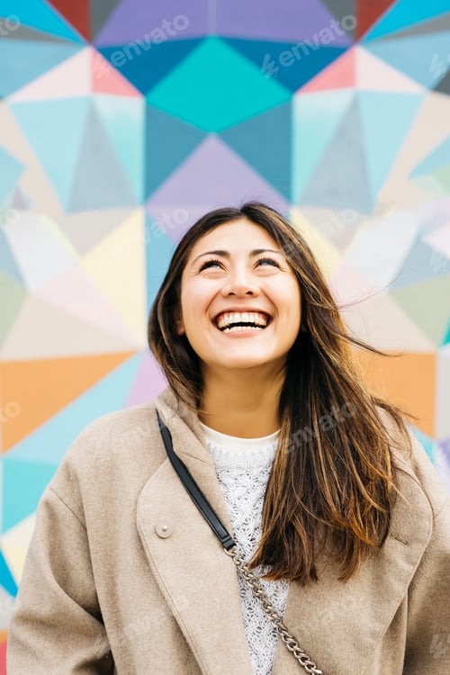 Preview: Young woman laughing looking up at colorful geometric background
