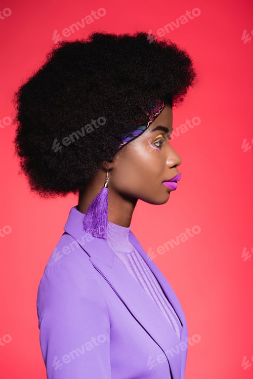 Preview: side view of african american young woman in purple stylish outfit isolated on red