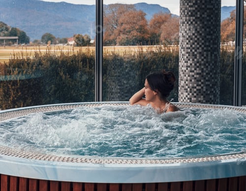 Preview: Attractive young woman relaxing in whirlpool in spa