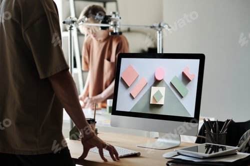 Visualização: Jovem fotógrafo masculino em pé na mesa com monitor de computador