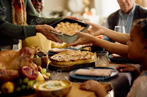 Preview: Close up of woman serving food at dining table during Thanksgiving dinner.