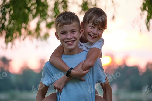 Preview: Happy siblings hugging lovingly in summer park. Young children brother and sister embracing each
