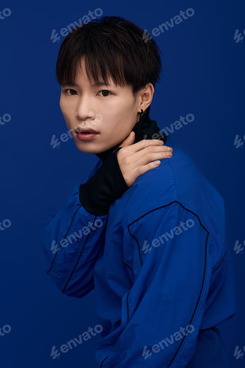 Preview: Handsome young asian man striking a pose against a vibrant blue backdrop in urban setting