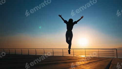 Preview: Silhouette of Young woman jumping on beach .