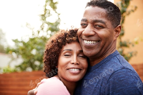Preview: Happy middle aged black couple embracing smile to camera, close up