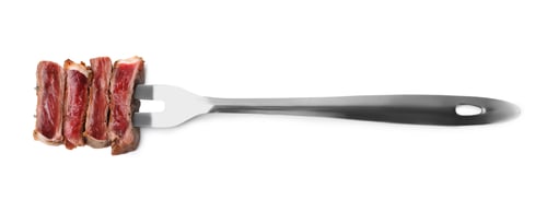 Preview: Carving fork with pieces of delicious beef meat isolated on white, top view