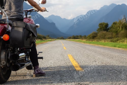 Visualização: Woman riding a motorcycle on a scenic road surrounded by Canadian Mountains