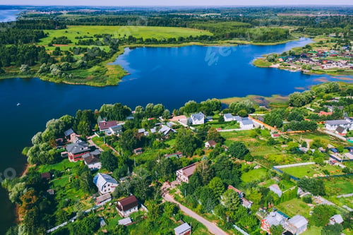 Preview: Aerial View of Serene Rural Landscape with Houses Alongside a Peaceful Lake and Lush Greenery