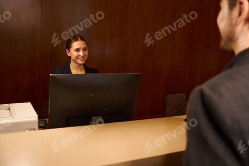Preview: Smiling woman receptionist welcoming visitor at hotel