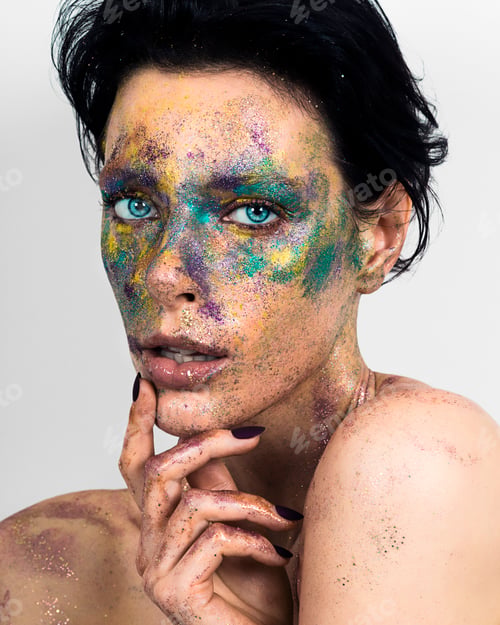 Preview: Woman with colorful powder makeup on her face posing against a white background