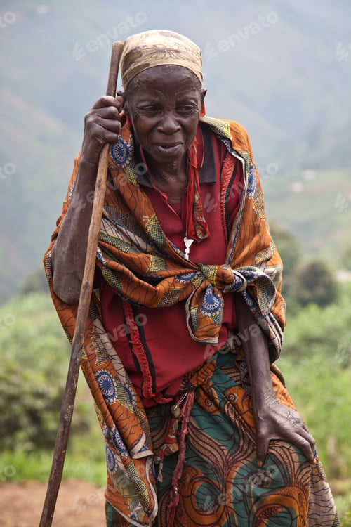 Preview: Elderly woman leaning on a stick with a thoughtful expression in a rural setting.
