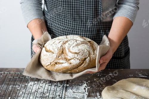 Preview: Baker holding freshly baked loaf of rye bread