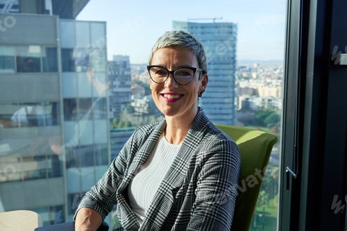 Preview: Portrait of a caucasian businesswoman smiling in modern office with city views.