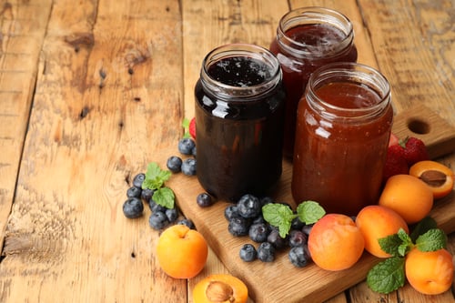 Preview: Different jams in jars and ingredients on wooden table. Space for text