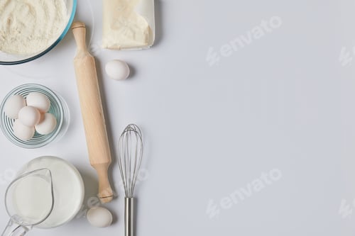 Preview: top view of eggs, milk and rolling pin on white tabletop
