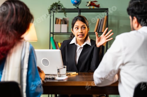 Preview: Indian professional executive meeting young couple in modern office with laptop for a deal
