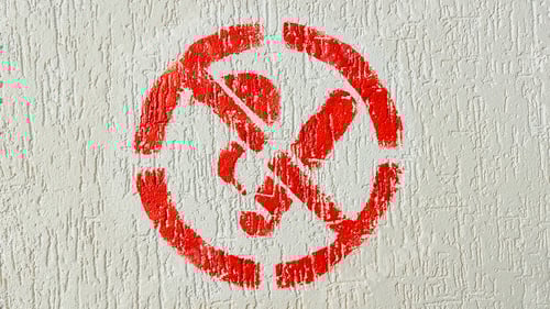 Preview: Red universal symbol prohibiting cigarette smoking painted on a textured off white wall surface
