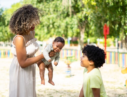 Preview: Latin mother with her two children, a boy and a baby enjoying a sunny day outdoors together