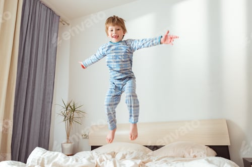Preview: Happy child having fun jumps and plays bed