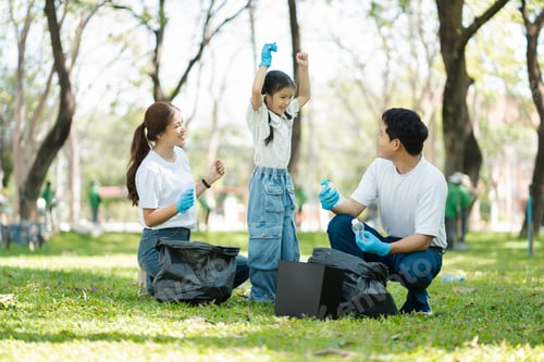 Preview: Happy Asian family collecting plastic bottles at the park.