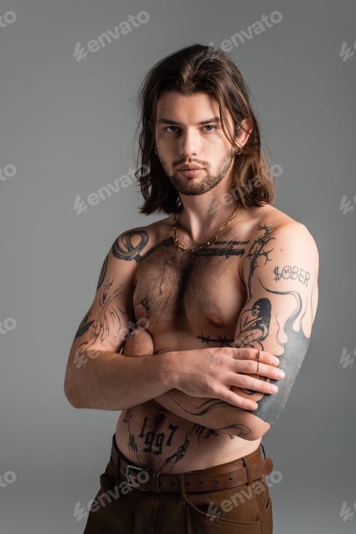 Preview: Muscular tattooed model posing while standing isolated on grey