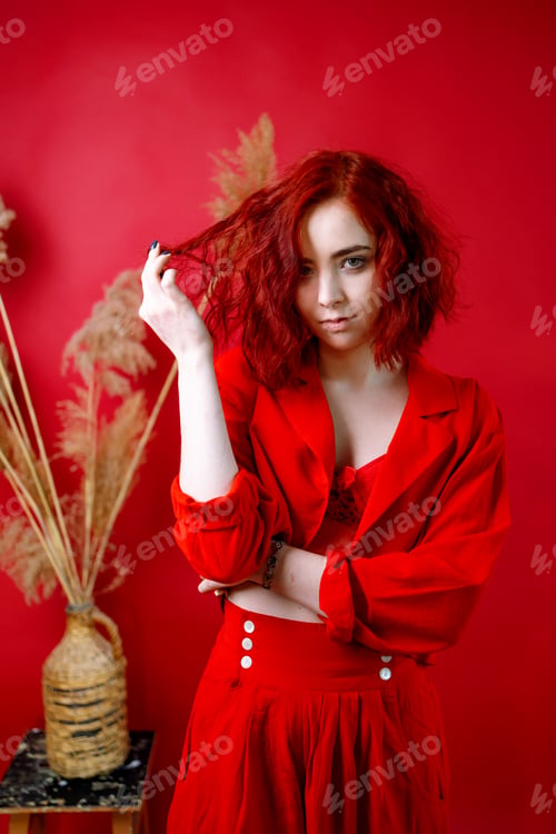Preview: Fashionable young woman in a red suit. Red background.
