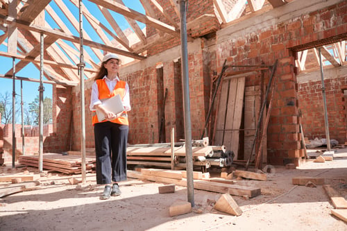 Preview: Responsible woman building engineer walking inside building with laptop